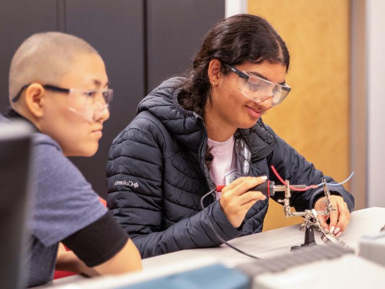 Two students soldering in engineering lab